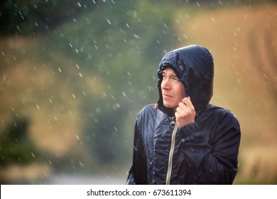 Young man walking in nature during heavy rain. 