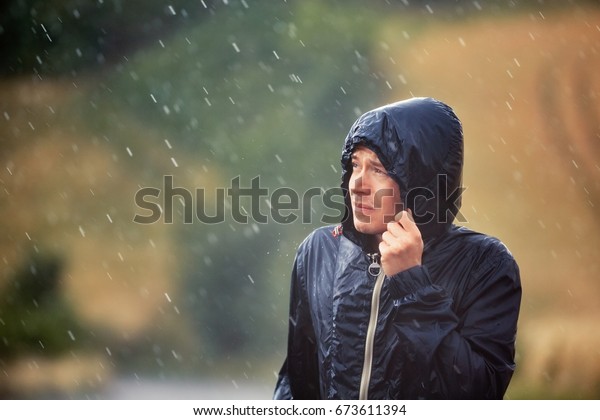 Young man\
walking in nature during heavy rain.\
