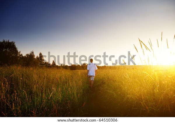 Young Man Walking On Field Stock Photo (Edit Now) 64510306