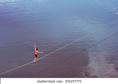 Young Man Walking On Tight Rope Over The Water
