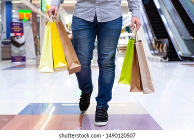 Young man walking with shopping bags down the city mall, crop