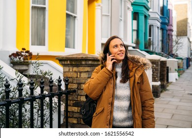 Young man walking through the colorful houses on Portobello Street in the Notting Hill neighborhood by using his smartphone - Powered by Shutterstock