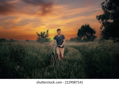 young man walks with a bicycle along a field road at sunset, an art photo of a lonely man.
