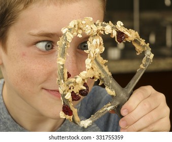 A Young Man Wanting To Eat The Oatmeal Cookie Dough On A Whisk