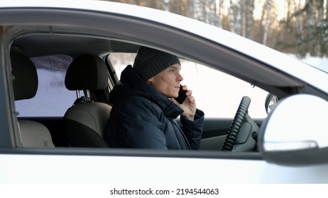 Young Man In Warm Clothes Talking On Phone While Sitting Inside The Car In Winter Day