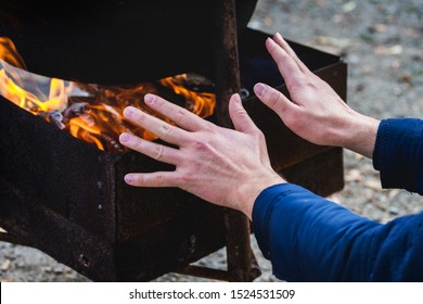 Young man warms his hands by the fire