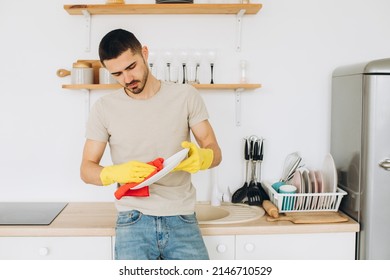 A young man washes dishes in the kitchen, wipes a plate. - Powered by Shutterstock