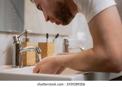 A Young Man Washes His Face In The Bathroom With A Splash Of Water. Hygiene And Cleanliness Of The Body. Morning Treatments For Men.