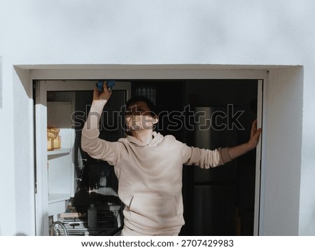A young man washes a plastic window frame with a blue rag.