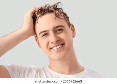 Young man washing hair against light background - Shutterstock ID 2366762663
