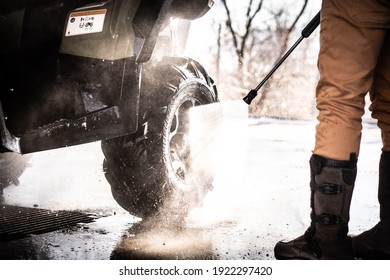 A Young Man Is Washing His Dirty ATV On The Car Wash.