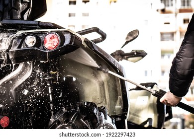 A Young Man Is Washing His Dirty ATV On The Car Wash.