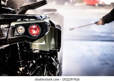 A Young Man Is Washing His Dirty ATV On The Car Wash.