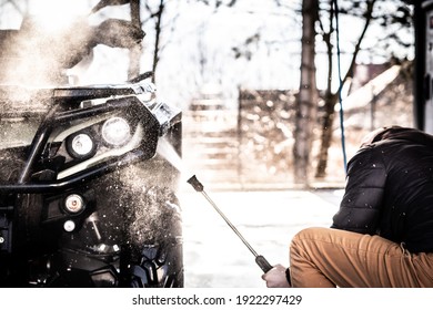 A Young Man Is Washing His Dirty ATV On The Car Wash.