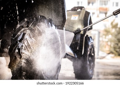 A Young Man Is Washing His Dirty ATV On The Car Wash.