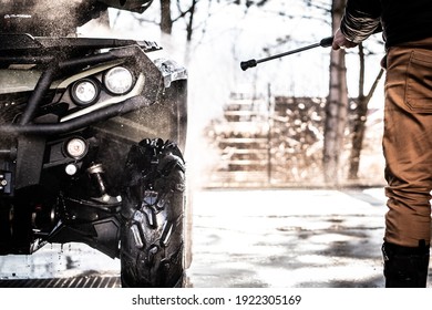 A Young Man Is Washing His Dirty ATV On The Car Wash.