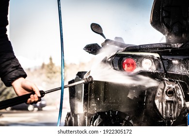 A Young Man Is Washing His Dirty ATV On The Car Wash.