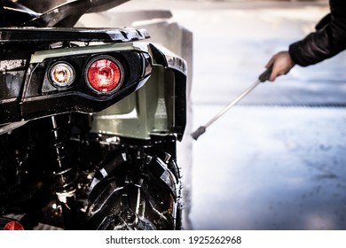 A Young Man Is Washing His Dirty ATV On The Car Wash.