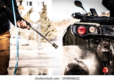 A Young Man Is Washing His Dirty ATV On The Car Wash.