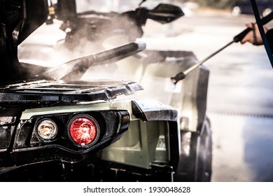 A Young Man Is Washing His Dirty ATV On The Car Wash.