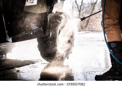 A Young Man Is Washing His Dirty ATV On The Car Wash.