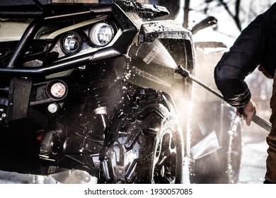 A Young Man Is Washing His Dirty ATV On The Car Wash.