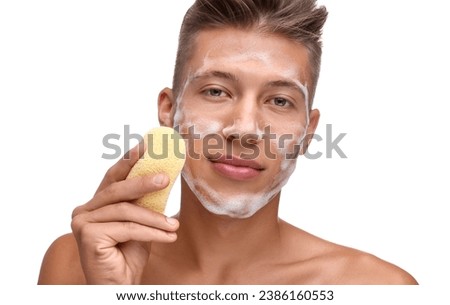 Young man washing his face with sponge on white background