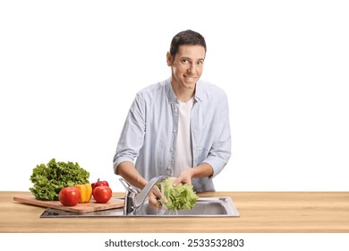 Young man washing vegetables in a sink and smiling isolated on white background - Powered by Shutterstock