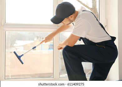 Young man washing window in office