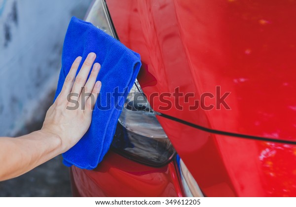 Young man\
washing and wiping a car in the\
outdoor