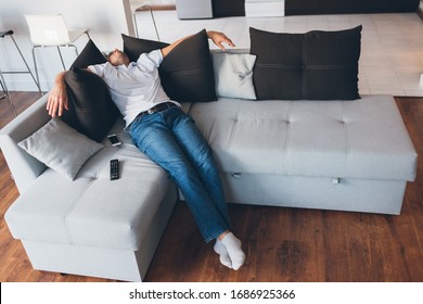 Young Man Watch Tv In His Own Apartment. Picture Of Guy In Deep Sleep Or Daydream. Sitting Or Lying On Couch And Hold Hands On Black Pillows. Sleep Alone In Room. Tired Exhausted Man