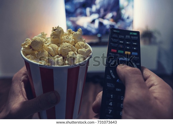 young man Watching a Movie in\
his living room with popcorn and remote control, Point of view\
shot
