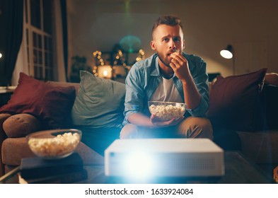 Young Man Watching Projector Tv At Home In The Evening Alone
