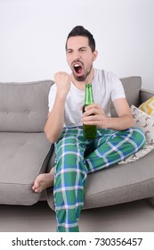 Young Man Watching Sport Tv With Beer And Celebrating. Indoors.