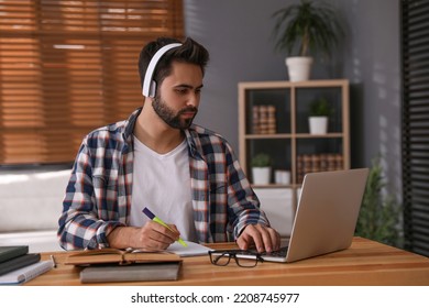 Young Man Watching Webinar At Table In Room