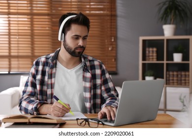 Young Man Watching Webinar At Table In Room