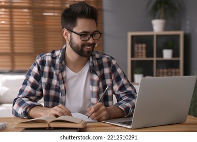 Young Man Watching Webinar At Table In Room