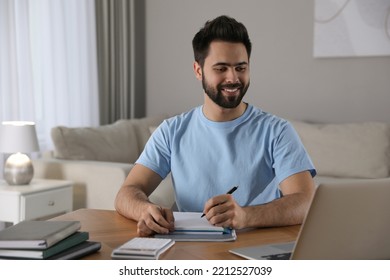 Young Man Watching Webinar At Table In Room