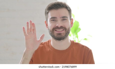 Young Man Waving Hand To Say Hello