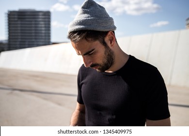 Young man wearing a beanie and a black t shirt outdoors