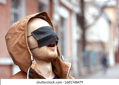Young man wearing black medical mask cover the eyes. Coronavirus quarantine situation. Ridiculous panic ridicule. Misinformation concept. Virus prevention. Pandemic Covid-19.