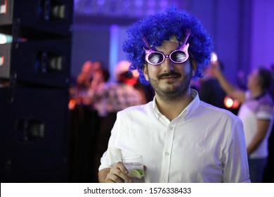 Young Man Wearing A Blue Toupee During The Eighties Party.