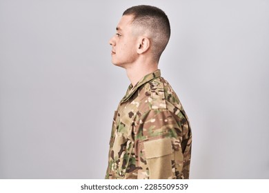 Young man wearing camouflage army uniform looking to side, relax profile pose with natural face with confident smile.  - Powered by Shutterstock