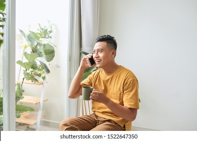 Young man wearing casual clothes talking on a mobile phone in the morning at a window - Powered by Shutterstock