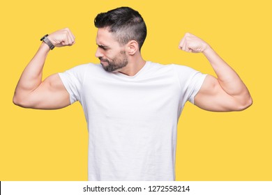 Young man wearing casual white t-shirt over isolated background showing arms muscles smiling proud. Fitness concept.