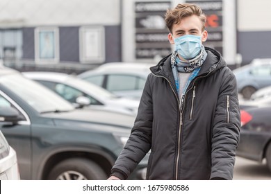 Young man wearing face mask, protection against coronavirus. Covid-19 person. Standing on big parking near supermarket, world amid corona virus situation