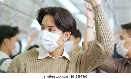 Young man wearing face mask travels on crowded subway train . Coronavirus disease or COVID 19 pandemic outbreak and urban lifestyle problem in rush hour concept . - Shutterstock ID 1845397363