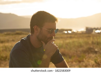 A young man, wearing glasses, concentrating on himself, meditates in a relaxed way, while enjoying the afternoon sun on a promenade in northern Spain. - Powered by Shutterstock