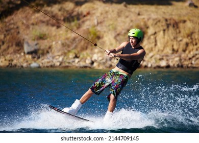 A Young Man Wearing A Helmut And Lifejacket Wakeboarding On A Lake. A Young Man Wearing A Helmet And Lifejacket Wakeboarding On A Lake.