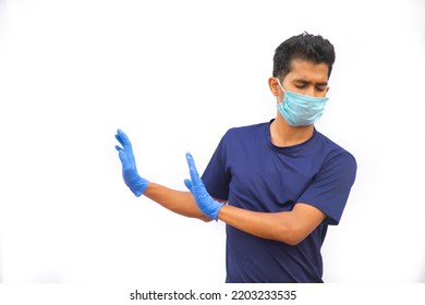 Young Man Wearing Mask, Making Stop Sign Gesture, Saying No Isolated On White Background  While Wearing Safety Mask And Gloves, Refusing Virus Disease, Close Up, Tell To Stop Or Stay Away.